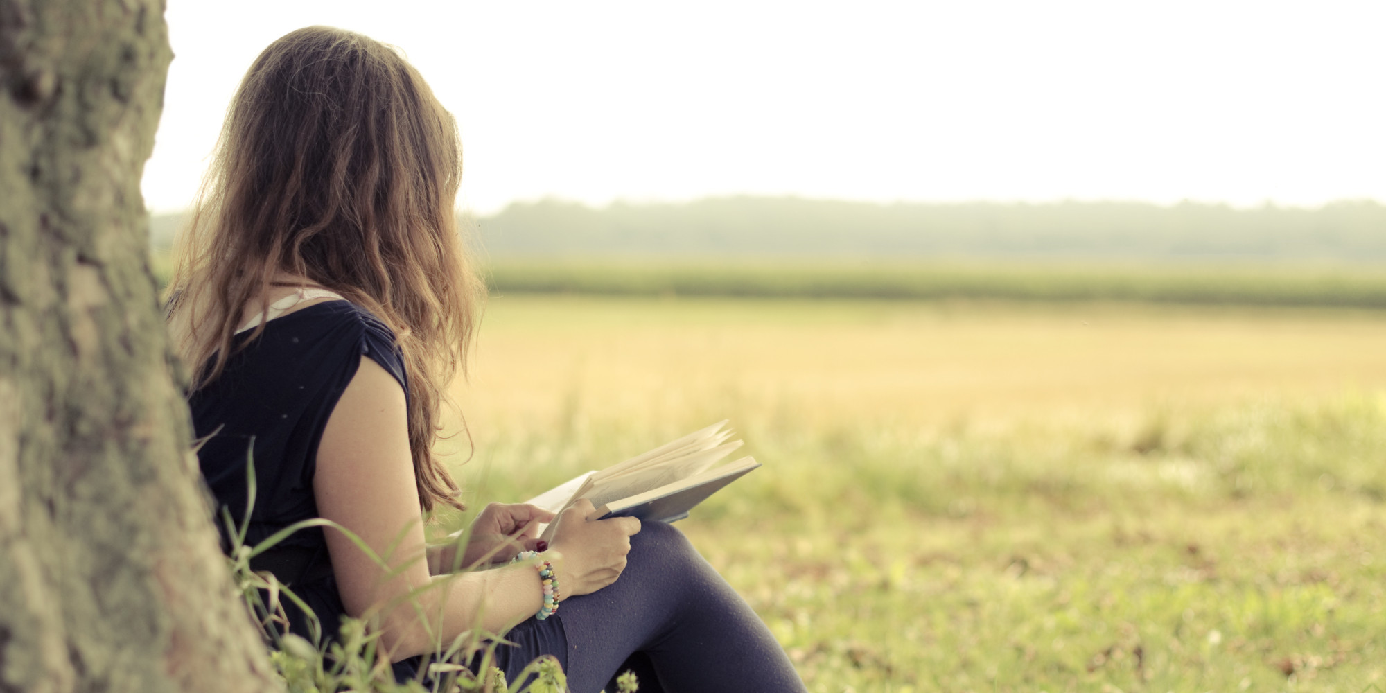 Woman in field reading Bible
